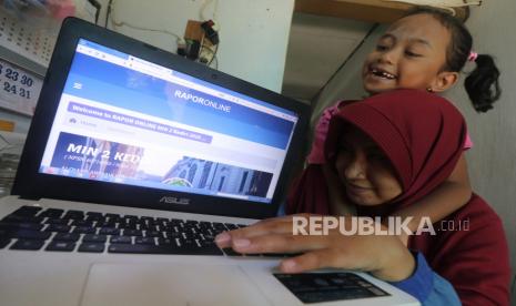 Orang tua bersama anaknya memantau rapor digital semester satu Madrasah Ibtidaiyah Negeri 2 Kediri di rumahnya, di Kota Kediri, Jawa Timur, Rabu (23/12/2020). Aplikasi raport digital berbasis Nomor Induk Siswa Nasional (NISN) tersebut dapat diakses oleh orang tua siswa tanpa harus mengambil rapor ke sekola guna mengantisipasi penyebaran COVID-19. 