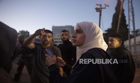 Warga Sheikh Jarrah Bertekad Pertahankan Tanah Mereka. Aktivis Palestina Muna al-Kurd, tengah, berdiri dengan aktivis lain ketika polisi Israel mendekati teman-teman mereka memperbaiki mural yang dirusak oleh pemukim Yahudi, di lingkungan Sheikh Jarrah di Yerusalem timur, di mana keluarga Palestina menghadapi penggusuran dari rumah mereka oleh Israel pemukim, Senin, 24 Mei 2021. 