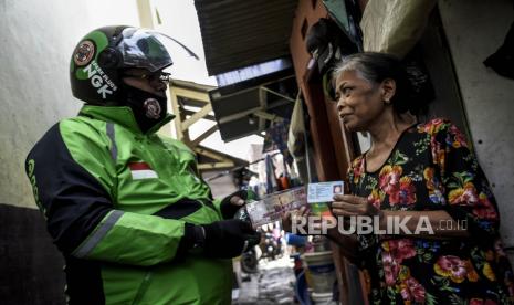 Pengemudi ojek daring memberikan paket bantuan sosial Pemerintah Provinsi Jawa Barat kepada warga di Jalan Cipagalo Girang, Buah Batu, Kota Bandung, Ahad (19/4). Distribusi bantuan sosial membutuhkan kerja keras aparat tingkat RT RW agar benar-benar sampai ke warga yang membutuhkan.