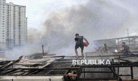 Warga berusaha memadamkan api yang membakar permukiman padat penduduk di kawasan Kebon Kosong, Kemayoran, Jakarta Pusat, Selasa (10/12/2024).