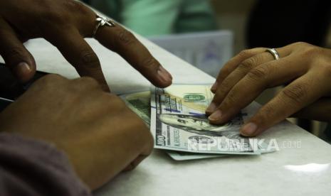 Teller melayani jual beli mata uang dolar AS di sebuah tempat penukaran uang, Jakarta, Rabu (6/7/2022). Ekonom senior Institute for Development of Economics and Finance (Indef) Nawir Messi mengingatkan, adanya risiko nilai tukar rupiah dapat melampaui target dalam APBN 2023 yang sebesar Rp 14.800 per dolar AS.