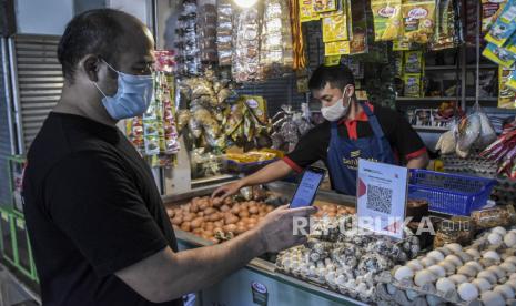 Warga melakukan transaksi digital saat berbelanja di salah satu kios di Pasar Atas Cimahi, CImahi Tengah, Kota Cimahi, Selasa (13/12/2022). Bank Indonesia menyatakan bahwa Quick Response Code Indonesian Standard (QRIS) yang merupakan standarisasi pembayaran menggunakan metode QR Code dari BI dapat membantu usaha mikro kecil dan menengah (UMKM) untuk naik kelas. 