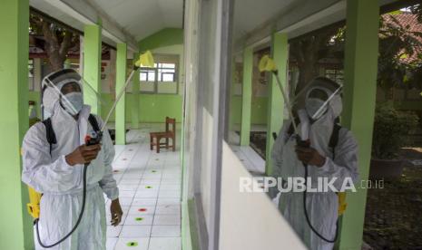 Petugas menyemprotkan cairan disinfektan di area SDN 065 Cihampelas yang ditutup sementara di Jalan Cihampelas, Kota Bandung, Senin (25/10). Pemerintah Kota Bandung melalui Dinas Pendidikan Kota Bandung menutup sementara 14 sekolah yang terdiri dari 5 SD, 2 SMP, 2 SMA, 4 SMK dan 1 SLB akibat temuan hasil positif Covid-19 saat tes usap PCR secara acak yang melebihi angka lima persen dari jumlah sampel. Foto: Republika/Abdan Syakura