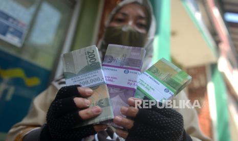 Warga menunjukan uang rupiah baru usai menukarkan di layanan kas keliling Bank Indonesia DIY, Pasar Beringharjo, Yogyakarta, Selasa (12/4/2022). Khusus di layanan kas Bank Indonesia warga harus melakukan registrasi dahulu di pintar.bi.go.id sehari sebelumnya. Jumlah uang yang ditukar maksimal berjumlah Rp 3,8 juta untuk setiap orang. Sementara itu, untuk penukaran di layanan bank BUMN tidak menggunakan registrasi dan warga hanya harus antre. Layanan penukaran uang ini untuk membantu masyarakat jelang Lebaran Idul Fitri 1443H.