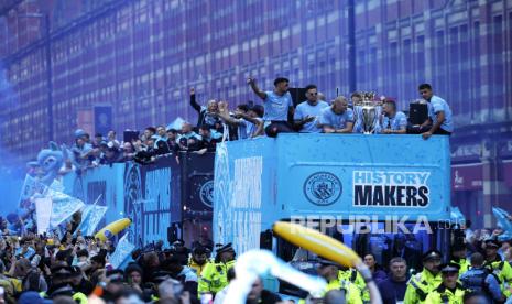 Pemain Manchester City membawa trofi Liga Premier Inggris di bus atap terbuka selama parade juara di Manchester, Ahad (26/5/2024). Ribuan suporter Manchester City tumpah ruah di jalanan Manchester sambil mengelu-elukan timnya setelah The Citizens memenangkan gelar Liga Premier keempat berturut-turut.