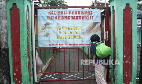 Warga keluar dari gang kampung yang dipasangi poster imbauan memakai masker di Gunungketur, Pakualaman, Yogyakarta, Senin (8/2/2021). Pemerintah Daerah Istimewa Yogyakarta memperpanjang  Pemberlakuan Pembatasan Kegiatan Masyarakat (PPKM) hingga tanggal 23 Februari 2021 sesuai arahan Presiden Joko Widodo untuk mengoptimalkan pengawasan pengetatan berskala mikro, yakni memotong penularan COVID-19 di level pedukuhan, kelurahan, RT dan RW. 