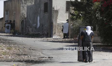 Para pengunjuk rasa Palestina menyaksikan pasukan Israel selama bentrokan setelah demonstrasi menentang pemukiman Israel di tanah desa Kafr Qadoum, dekat kota Nablus, Tepi Barat, 23 September 2022.