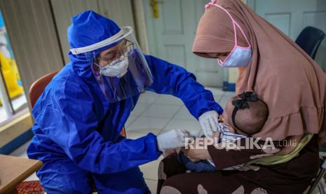 Petugas menggunakan alat pelindung diri (APD) saat memberikan imunsiasi kepada balita di Puskesmas Karawaci Baru, Kota Tangerang, Banten, Rabu (13/5/2020). Pelayanan imunisasi tersebut tetap dilakukan di tengah pandemi Covid-19 demi menjaga kesehatan anak.