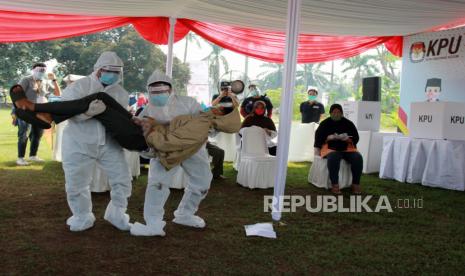 Petugas Kelompok Penyelenggara Pemungutan Suara (KPPS) dengan menggunakan alat pelindung diri (APD) lengkap mengevakuasi pemilih yang pingsan saat akan melakukan pencoblosan ketika Simulasi Pemungutan Suara dengan Protokol Kesehatan Pencegahan dan Pengendalian COVID-19 pada Pilkada Serentak 2020, di TPS 18 Cilenggang, Serpong, Tangerang Selatan, Banten, Sabtu (12/9/2020). Simulasi ini dilaksanakan dengan tujuan untuk memberikan pembelajaran kepada pemilih dalam melaksanakan pemungutan suara Pilkada Serentak 2020 ditengah pandemi COVID-19.