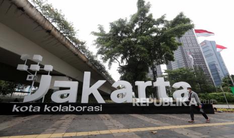 Warga berjalan di samping logo 'Jakarta Kota Kolaborasi' yang dipasang di bawah flyober Karet-Sudirman. Kini logo tersebut hilang seiring dengan Penjabat Gubernur DKI Heru Budi Hartono yang memiliki slogan Sukses Jakarta untuk  Indonesia.