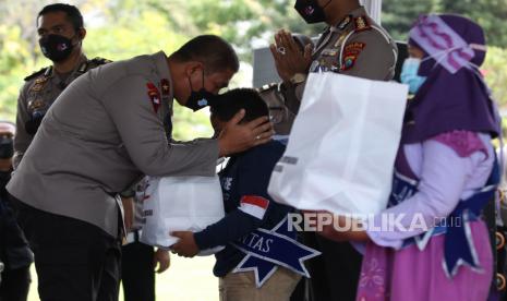 Wakapolda Jawa Timur Brigjen Pol Slamet Hadi Supraptoyo (kiri) mencium kening seorang anak asuh saat peringatan Hari Lalulintas Bhayangkara di Tugu Pahlawan, Surabaya, Jawa Timur, Jumat (17/9/2021). Direktorat Lalu lintas (Ditlantas) Polda Jawa Timur menggelar berbagai kegiatan untuk menyambut Hari Lalulintas Bhayangkara salah satunya dengan mengadakan program pengangkatan orang tua asuh bagi anak yatim piatu terdampak COVID-19 bernama Satu Polantas Satu Anak Yatim Piatu.  