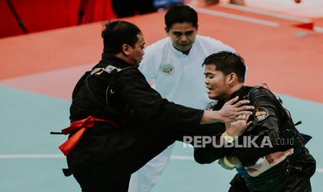 Pesilat Papua, Putra Hidayana berusaha menjatuhkan pesilat D.I Yogyakarta Firdhana W P pada laga final pencak silat kelas J 90-95 kg putra di GOR Toware, Sentani, Kabupaten Jayapura, Papua (12/10). Pesilat Papua, Putra Hidayana berhasil menang melawan pesilat D.I Yogyakarta Firdhana W P dan berhak meraih medali emas di kelas J 90-95 kg. Republika/Thoudy Badai