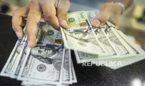 Karyawan menghitung uang dolar di gerai penukaran mata uang asing Ayu Masagung, Jakarta, Senin (18/5). Nilai tukar dolar AS meningkat di dekat tertinggi satu minggu terhadap mata uang utama lainnya di perdagangan Asia pada Rabu (8/9) pagi. 