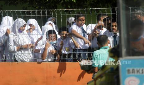   Siswa membeli makanan ringan dari pedagang kaki lima melalui pagar pada hari sekolah di Banda Aceh, Aceh, Senin (11/1/2021). Aceh menjadi daerah yang dikecualikan dari SKB tiga menteri tentang pengguanaan seragam dan atribut di sekolah negeri. (ilustrasi)