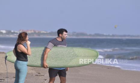 Wisatawan mancanegara membawa papan selancar di Pantai Canggu, Badung, Bali, Kamis (27/8/2020). Pemerintah Provinsi Bali memutuskan untuk menunda pembukaan wilayah untuk kunjungan wisatawan mancanegara yang awalnya direncanakan dibuka mulai 11 September 2020 karena perkembangan kasus positif COVID-19 yang masih fluktuatif serta sejumlah persoalan dan pertimbangan lain.