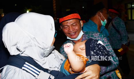 Jamaah haji menyapa kerabatnya setibanya di Wisma Haji Kota Madiun, Jawa Timur, Rabu (20/7/2022) malam. Dari 90 jamaah haji asal Kota Madiun, satu orang terkonfirmasi positif COVID-19 dan harus menjalani isolasi di Surabaya, sedangkan seluruh jamaah haji lainnya diharuskan menjalani isolasi mandiri selama dua minggu. 