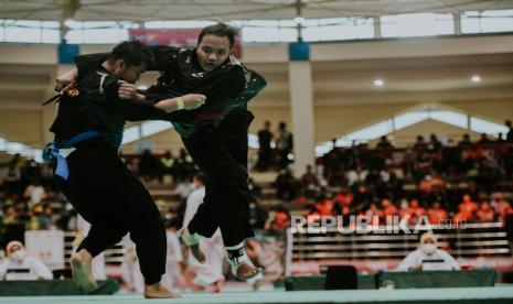 Pesilat Papua, Putra Hidayana berusaha menjatuhkan pesilat D.I Yogyakarta Firdhana W P pada laga final pencak silat kelas J 90-95 kg putra di GOR Toware, Sentani, Kabupaten Jayapura, Papua (12/10). Pesilat Papua, Putra Hidayana berhasil menang melawan pesilat D.I Yogyakarta Firdhana W P dan berhak meraih medali emas di kelas J 90-95 kg. Republika/Thoudy Badai