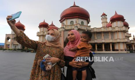 Warga berswafoto dengan latar Masjid Agung Baitul Makmur di Meulaboh, Aceh Barat. Pengaturan prokes tempat wisata sangat penting dilakukan untuk mencegah lonjakan penularan Covid-19 pasca Lebaran. Jangan sampai setelah libur Lebaran, kasus Covid-19 naik tinggi akibat tempat-tempat wisata dibiarkan bebas tanpa aturan. 