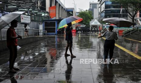 Nita (33) bersama temannya saat menjajakan jasa ojek payung di area Stasiun Sudirman, Jakarta, Kamis (4/7/2024). Jasa ojek tersebut tidak dipatok harga atau dibayar seikhlasnya. Sekali ngojek, biasanya Nita mendapatkan upah sebesar Rp5.000 hingga Rp10.000 dari pengguna jasanya.