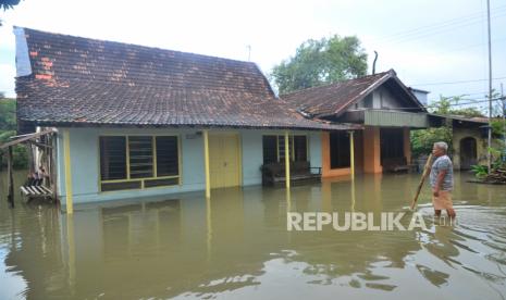 Warga berjalan di depan rumah yang tergenang air di Desa Tanjungkarang, Jati, Kudus, Jawa Tengah, Senin (28/2/2022). Akibat curah hujan yang tinggi serta drainase yang buruk menyebabkan puluhan rumah serta beberapa jalan utama di desa itu terendam banjir. 