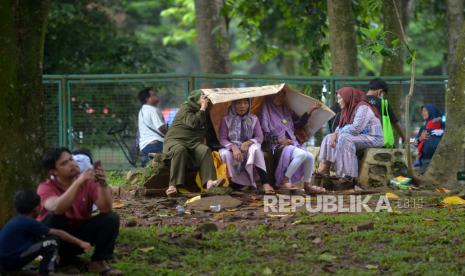 Pengunjung berteduh ketika mengunjungi Taman Margasatwa Ragunan di Jakarta.