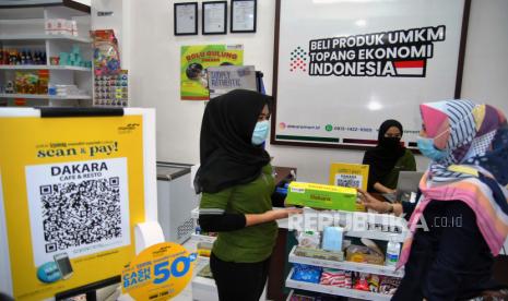 Nasabah Bank Mandiri Syariah berbincang dengan pelayan toko saat menggunakan layanan digital di Pusat Oleh-oleh UMKM Indonesia Dakara Mart, Dramaga, Kabupaten Bogor, Jawa Barat, Selasa (20/10/2020). Bank Mandiri Syariah terus fokus dan mengutamakan layanan digital banking untuk memenuhi kebutuhan berbagai transaksi nasabah yang meningkat di masa Adaptasi Kebiasaan Baru (AKB) melalui standarisasi pembayaran digital menggunakan QR Code (QRIS) sehingga masyarakat tidak perlu menggunakan uang tunai untuk mengurangi risiko penularan COVID-19. 