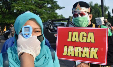 Petugas memeriksa suhu tubuh pengunjung di jalan masuk kawasan hari bebas kendaraan bermotor atau ‘car free day’ Taman Lalu Lintas Bantaran Sungai Madiun di Kota Madiun, Jawa Timur, Ahad (7/6/2020). Pemkot Madiun membuka kembali kawasan tersebut setelah sebelumnya selama sekitar tiga bulan ditiadakan, dengan menerapkan protokol kesehatan guna pencegahan penularan COVID-19, antara lain menjalani pemeriksaan suhu tubuh, mengenakan masker, cuci tangan dan menjaga jarak