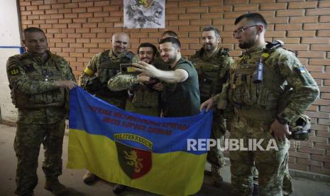 Dalam foto ini disediakan oleh Kantor Pers Kepresidenan Ukraina, Presiden Ukraina Volodymyr Zelenskyy, kanan tengah, berfoto selfie dengan prajurit di dekat garis depan di wilayah Donetsk, Ukraina, Minggu, 5 Juni 2022.