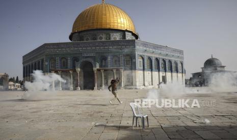 Pria Palestina melarikan diri dari gas air mata saat bentrokan dengan pasukan keamanan Israel di depan Masjid Kubah Batu di kompleks Masjid Al Aqsa di Kota Tua Yerusalem Senin (10/5).