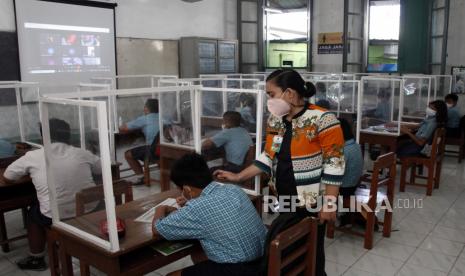 Guru SD Warga Solo menerangkan materi pembelajaran kepada siswanya dengan sistem kombinasi antara tatap muka terbatas dengan pembelajaran secara daring di Solo, Jawa Tengah, Kamis (2/9/2021). Pemerintah Kota Solo mulai mengizinkan pelaksanaan PTM secara terbatas dengan menerapkan protokol kesehatan guna mencegah penyebaran COVID-19. 