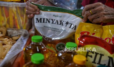 Pedagang menunjukan Minyakita di sebuah warung klontong di Jakarta, Senin (22/7/2024).