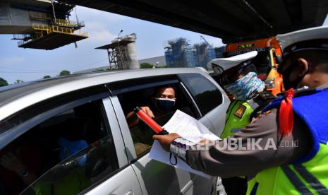 Petugas kepolisian memeriksa warga yang melintas. Ilustrasi