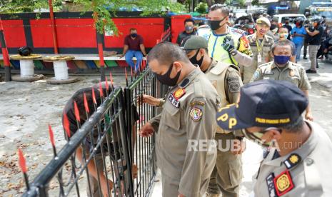 Sejumlah petugas berusaha masuk ke dalam toko pakaian yang masih buka dan melayani pembeli secara sembunyi-sembunyi di jl HB Yassin, Kota Gorontalo, Gorontalo, Sabtu (23/5/2020). Petugas gabungan Satpol PP dan Kepolisian menertibkan dan menutup sejumlah toko selain bahan pangan, kesehatan dan keperluan harian yang masih buka dalam rangka penerapan Pembatasan Sosial Berskala Besar (PSBB) guna mencegah penyebaran COVID-19