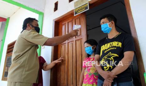 Petugas mengukur suhu tubuh warga yang pulang dari perantauan dan menjalani karantina selama 14 hari di SDN Desa Kebonagung, Kecamatan Ploso, Kabupaten Jombang, Jawa Timur, Senin (13/4/2020). Berdasarkan data Gugus Tugas Penanganan COVID-19 Kabupaten Jombang, hingga Senin (13/4/2020) jumlah kasus positif bertambah menjadi empat orang, sedangkan 467 kasus Orang Dalam Pemantauan (ODP) serta lima kasus Pasien Dalam Pengawasan (PDP)