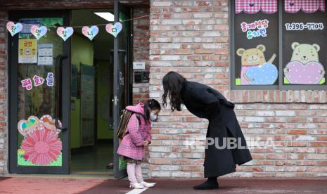  Seorang guru dan siswanya saling menyapa di sebuah taman kanak-kanak di Seoul, Korea Selatan