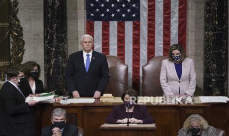  Wakil Presiden Mike Pence dan Ketua DPR Nancy Pelosi, D-Calif., Berdiri setelah membaca sertifikasi akhir dari suara Electoral College yang diberikan dalam pemilihan presiden November selama sesi bersama Kongres setelah bekerja sepanjang malam, di Capitol di Washington , Kamis, 7 Januari 2021. Pengunjuk rasa yang kejam yang setia kepada Presiden Donald Trump menyerbu Capitol pada hari Rabu, mengganggu proses tersebut.