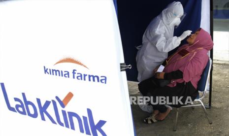 A Kimia Farma' s medical worker carries out an antigen rapid test to a resident who want travelling out of town