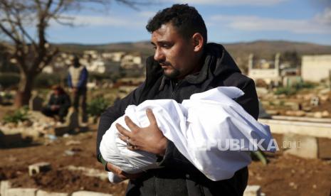  Seorang pria membawa jenazah anggota keluarga yang meninggal dalam gempa dahsyat yang mengguncang Suriah dan Turki di pemakaman di kota Jinderis, provinsi Aleppo, Suriah, Selasa (7/2/2023). Seorang bayi perempuan ditemukan terkubur di bawah puing-puing dengan tali pusar masih terhubung dengan ibunya, Afraa Abu Hadiya, yang ditemukan tewas, menurut kerabat dan dokter. Bayi itu adalah satu-satunya anggota keluarganya yang selamat dari bangunan yang runtuh pada Senin di Jinderis, di sebelah perbatasan Turki, Ramadan Sleiman, seorang kerabat, mengatakan kepada The Associated Press.