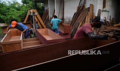 Pekerja menyelesaikan pembuatan peti jenazah COVID-19 di Surabaya, Jawa Timur, Kamis (21/1/2021). Perajin tersebut mengirim sedikitnya 12 peti mati untuk salah satu rumah sakit rujukan COVID-19 di Surabaya dan dapat menyelesaikan sekitar 30 peti dalam sehari. 