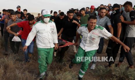 Petugas medis mengevakuasi orang yang terluka dari pagar perbatasan Jalur Gaza dengan Israel, selama protes menandai peringatan serangan pembakaran 1969 di masjid Al-Aqsa Yerusalem oleh seorang turis Australia yang kemudian ditemukan sakit jiwa, di sebelah timur Kota Gaza, Sabtu. 21 Agustus 2021.