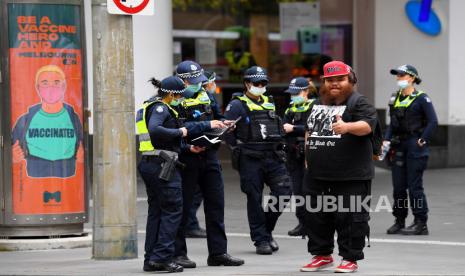 Petugas polisi Victoria berbicara dengan seseorang yang memberi isyarat sambil difoto menjelang rapat umum yang direncanakan menentang vaksinasi wajib COVID-19 di Melbourne, Victoria, Australia, 24 September 2021.