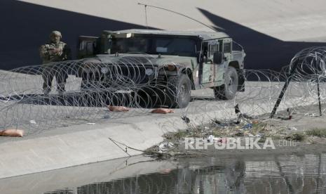 Seorang tentara AS berdiri di samping kendaraannya saat dia menjaga perbatasan antara Meksiko dan Amerika Serikat