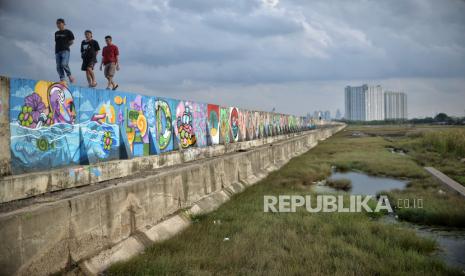 Warga beraktivitas di area tanggul Muara Baru, Jakarta, Senin (2/1/2023). Menurut Pengamat Tata Kota Nirwono Yoga mengatakan keberadaan tanggul laut raksasa atau giant sea wall dinilai tak mampu atasi banjir rob di pesisir Jakarta. Namun menurutnya, reforestasi hutan mangrove merupakan benteng alami yang ramah lingkungan guna mengatasi banjir rob tersebut.  