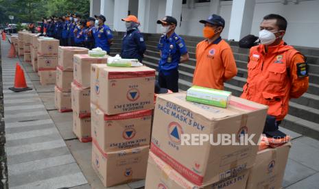 Petugas Badan Nasional Penanggulangan Bencana (BNPB) dan Damkar Kota Bandung bersiap membagikan ribuan masker kepada kepada warga di Plaza Balai Kota, Sabtu (19/2/2022). Pembagian masker gratis untuk masyarakat merupakan program nasional yang dilakukan hingga Mei 2022 dengan target 15 juta masker, sebagai upaya mengurangi penyebaran Covid-19.