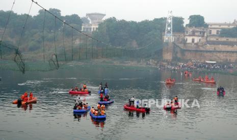 Warga India berkumpul saat personel Pasukan Tanggap Bencana Nasional (NDRF) bekerja di lokasi setelah jembatan gantung berusia 100 tahun runtuh di Morbi, Gujarat, India, 31 Oktober 2022. Menurut pejabat polisi di Gujarat, setidaknya 141 orang telah telah dilaporkan meninggal dalam insiden tersebut.