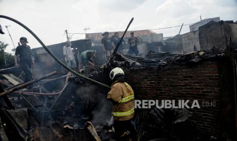 Personel Damkar melakukan pendinginan pascakebakaran di permukiman padat penduduk Kramat Pulo, Senen, Jakarta, Rabu (15/12). Sebanyak 17 mobil pemadam kebakaran dikerahkan untuk memadamkan api yang menghanguskan permukiman warga. Kebakaran terjadi pada pukul 08.37 WIB diduga akibat korsleting listrik yang menyebabkan sekitar 25 petak rumah hangus terbakar. 