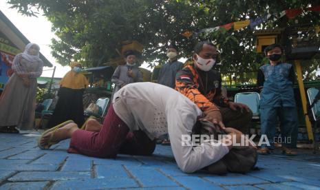 Relawan dari BPBD Jawa Timur Mahmudi (kedua kanan) mengajarkan cara melindungi kepala menggunakan tas sekolah saat simulasi dan edukasi tentang bencana gempa bumi di halaman Koramil 0831/04 Sukolilo, Surabaya, Jawa Timur. DPRD sebut anggaran BPBD Surabaya difokuskan untuk operasional tanggap bencana.