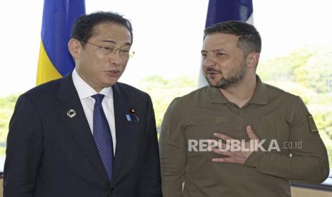  Presiden Ukraina Volodymyr Zelenskyy (kanan) berbincang dengan Perdana Menteri Jepang Fumio Kishida, dalam sesi foto bersama, menjelang sesi kerja mengenai Ukraina pada KTT G7 di Hiroshima, Jepang barat,  Ahad (21/5/2023) 