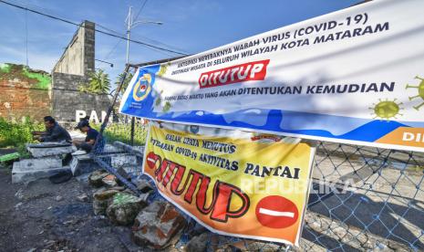 Sejumlah petugas berjaga saat melakukan penutupan akses masuk ke tempat wisata pantai Ampenan di Mataram, NTB, Ahad (31/5/2020). Pemerintah Kota Mataram menutup sejumlah tempat wisata dan akses masuk ke Kota Mataram guna mencegah keramaian warga dan antisipasi penyebaran COVID-19 saat merayakan tradisi “lebaran topat” (tradisi lebaran yang dirayakan seminggu setelah hari raya Idul Fitri) di Lombok yang biasanya dirayakan dengan bersilaturrahmi keliling kerumah keluarga, ziarah makam dan mengunjungi pantai untuk berwisata