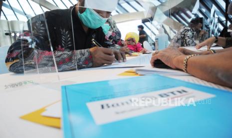 Pekerja yang mendapatkan Manfaat Layanan Tambahan (MLT) dari program Jaminan Hari Tua (JHT) menyelesaikan proses administrasi saat proses akad kredit massal  di Serpong, Tangerang (30/11).  Bank BTN berkolaborasi dengan Kementerian Ketenagakerjaan dan BP Jamsostek menggelar akad massal kredit rumah pekerja MLT program Jaminan Hari Tua guna memperluas fasilitas pembiayaan kepada pada pekerja diantaranya fasilitas kredit kepemilikan rumah dan renovasi rumah dan menargetkan realisasi kredit MLT tersebut mencapai Rp100 miliar hingga akhir tahun 2021. Foto: Tahta Aidilla/Republika.